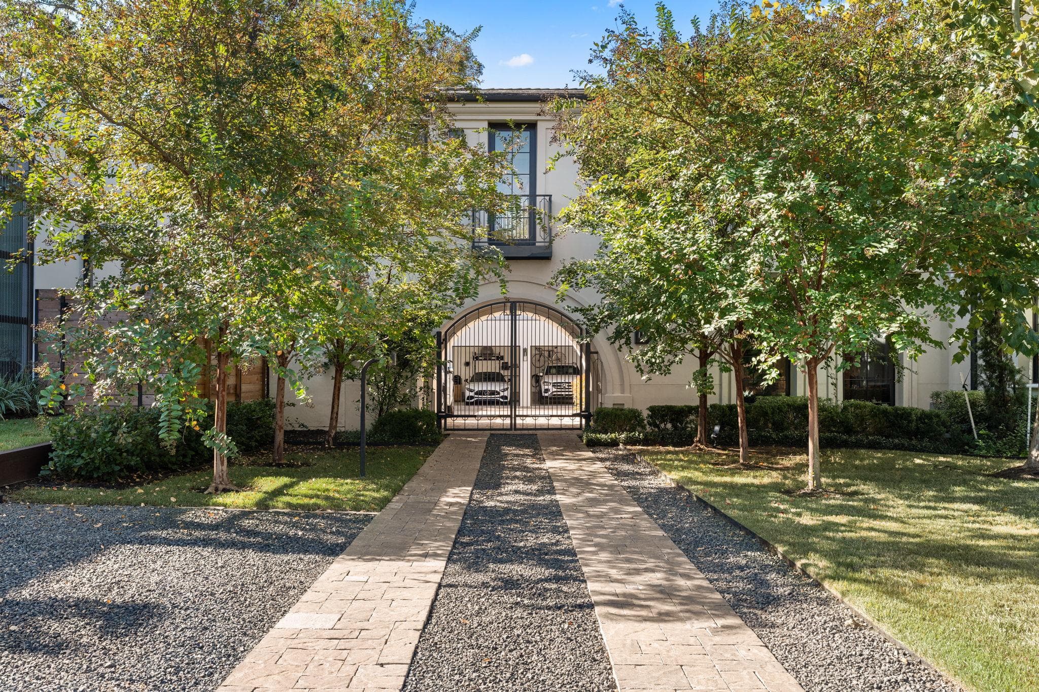 Mature trees frame a paved driveway leading to a