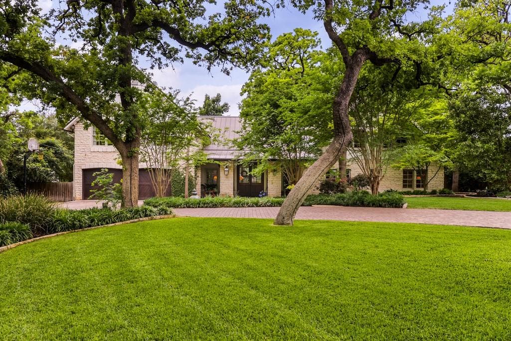 Expansive front lawn with a brick paver driveway